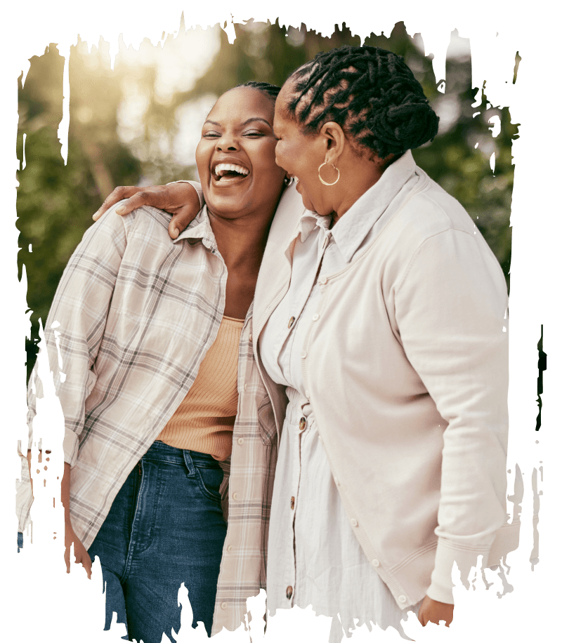 Two women laughing with one arm around each other.